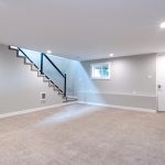 Light spacious basement area with staircase and light gray walls with carpet